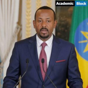 Abiy Ahmed delivering a speech at a podium, wearing a blue suit with Ethiopian flags in the background.