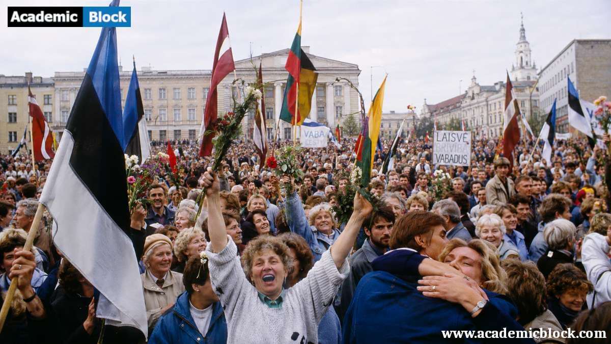 Image showing crowds gathered in a Baltic capital city square during the restoration of independence in 1990–1991. Citizens cheer while raising Estonian, Latvian, and Lithuanian flags.