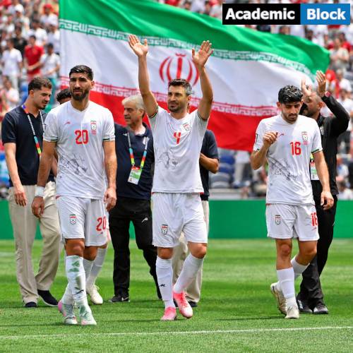 Sardar Azmoun, Shoja Khalilzadeh, and Mehdi Torabi in white jerseys and walk across the pitch, raising their hands to the crowd, with a large Iran flag waving in the stadium background.