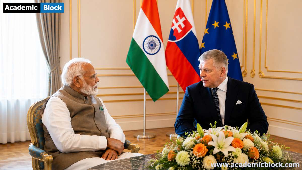 Prime Minister Narendra Modi shakes hands with Slovak Prime Minister Robert Fico during an official meeting in Slovakia, with the Indian, Slovak, and EU flags displayed in the background.