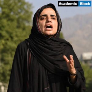 Mahrang Baloch speaks passionately during a public gathering, wearing a black dress and headscarf against an outdoor background.