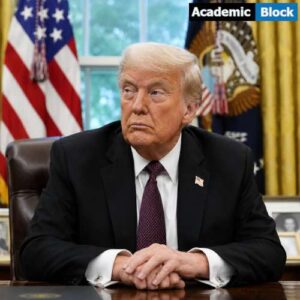 Donald Trump sits at a desk in a formal office, wearing a black suit and tie, with U.S. flags and official decor visible in the background.