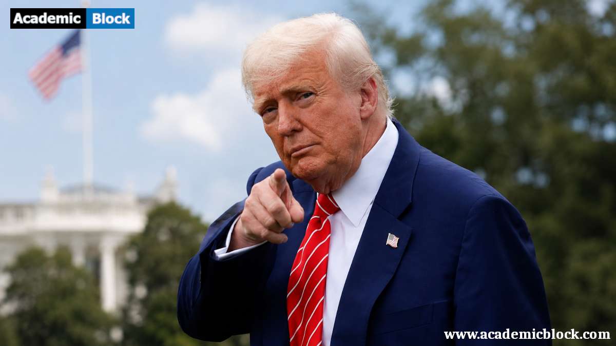 Donald Trump points toward the camera while standing outdoors in a dark suit and red tie, with a blurred White House-style building and American flag in the background.