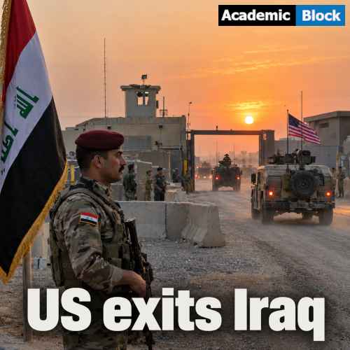 An Iraqi soldier stays stationed on his post as a U.S. military convoy leaves a military compound at sunset, with the Iraqi flag, concrete barriers, and base buildings in the background.